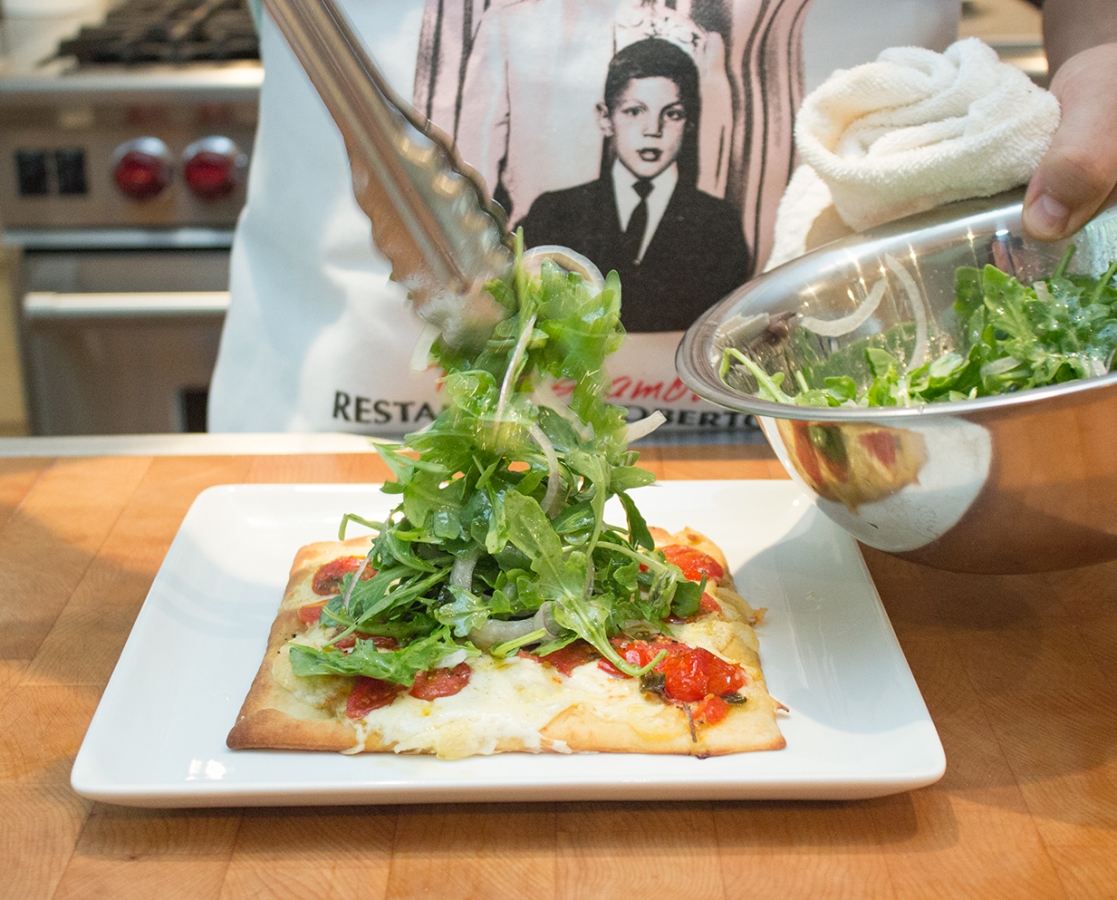 Slow roasted cherry tomato pizza with mozzarella topped with arugula salad