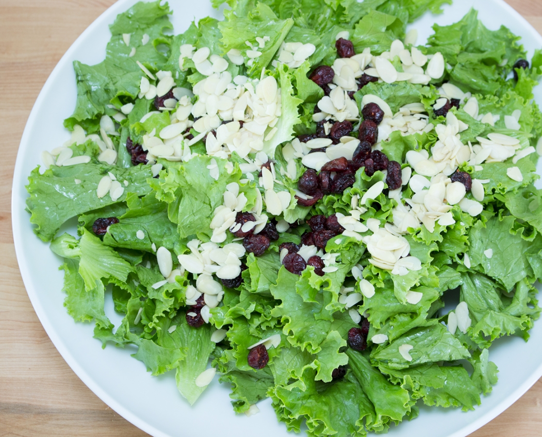 Salade verte rehaussée d’une vinaigrette orange et miel, parsemée de canneberges séchées et d’amandes tranchées