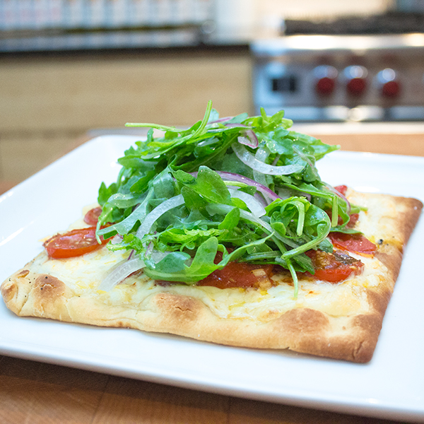 Pizza à la tomate cerise rôtie, mozzarella et salade de roquette