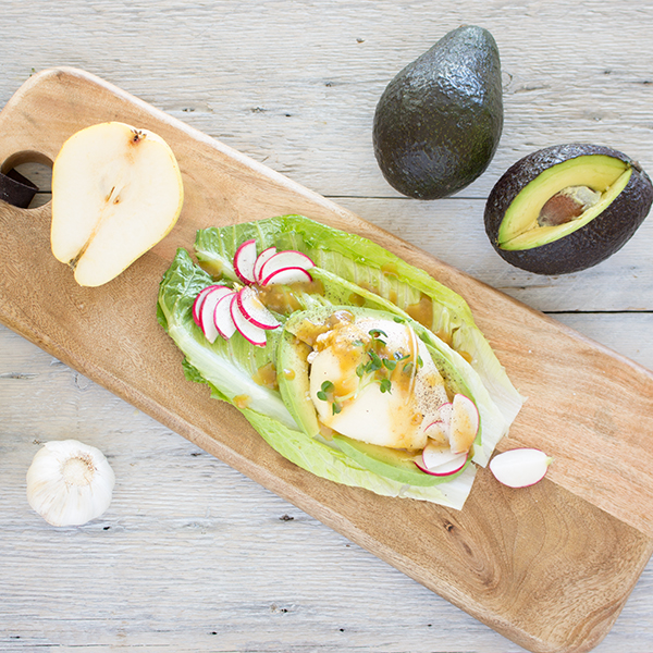 Fresh pear stuffed with mascarpone and walnut on fresh romaine leaves in a garlic dressing